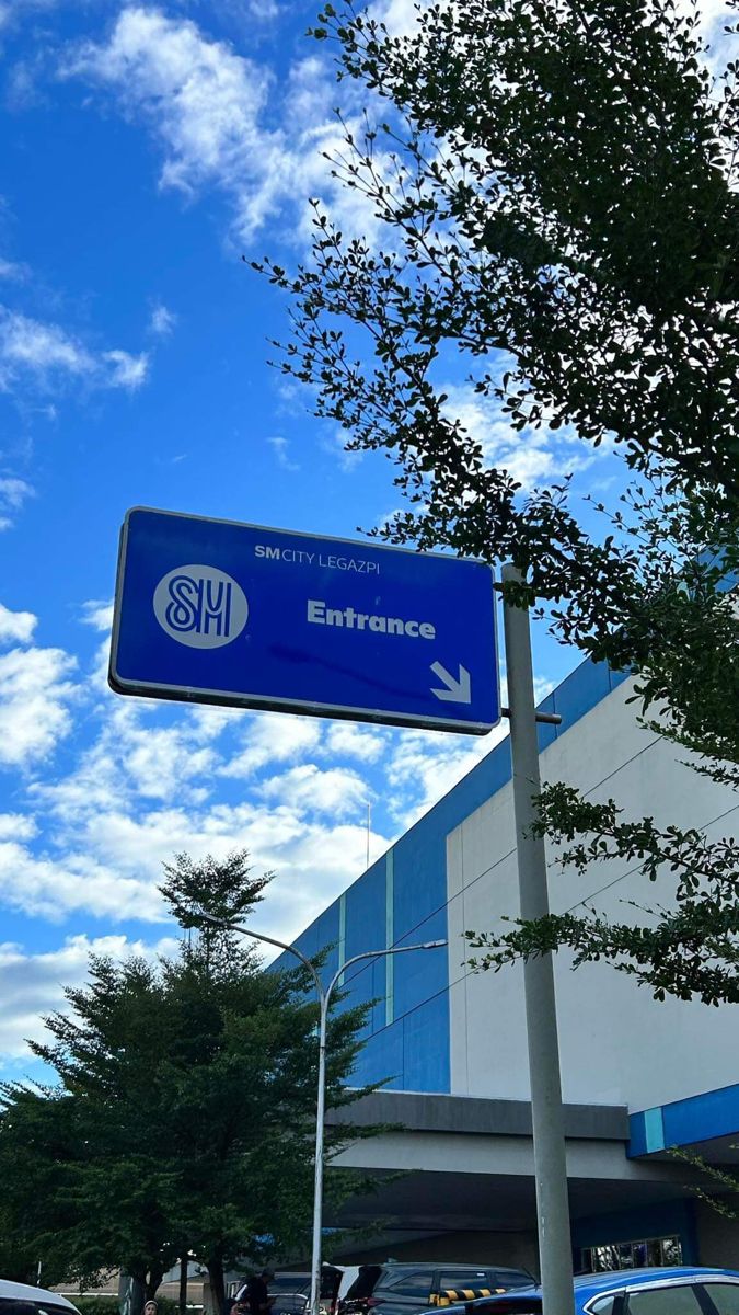 a blue street sign sitting on the side of a road next to a tall building