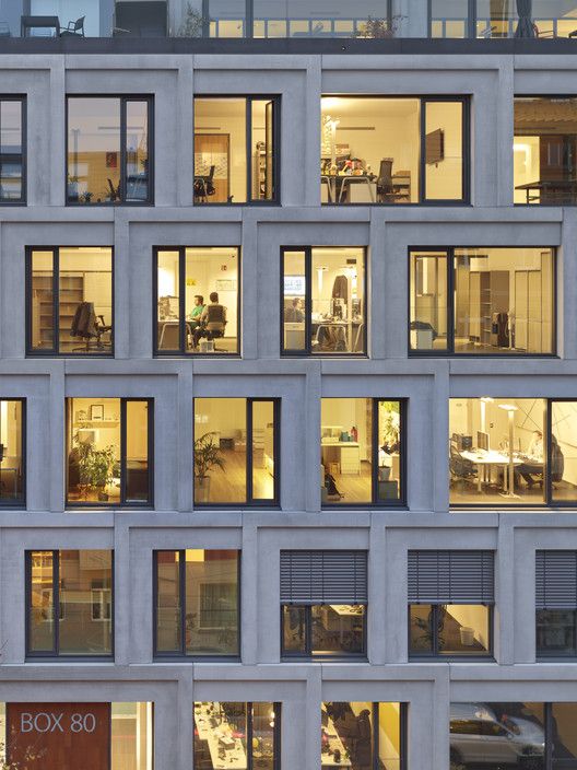 an office building with many windows and people working at their desks