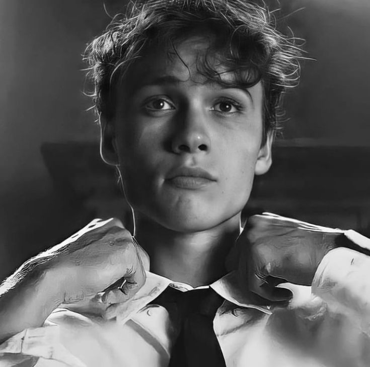 black and white photograph of a young man adjusting his tie