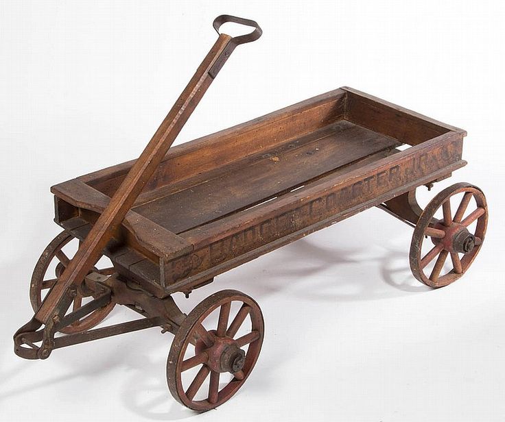 an old fashioned wooden wagon with wheels and a shovel on the top, sitting upright