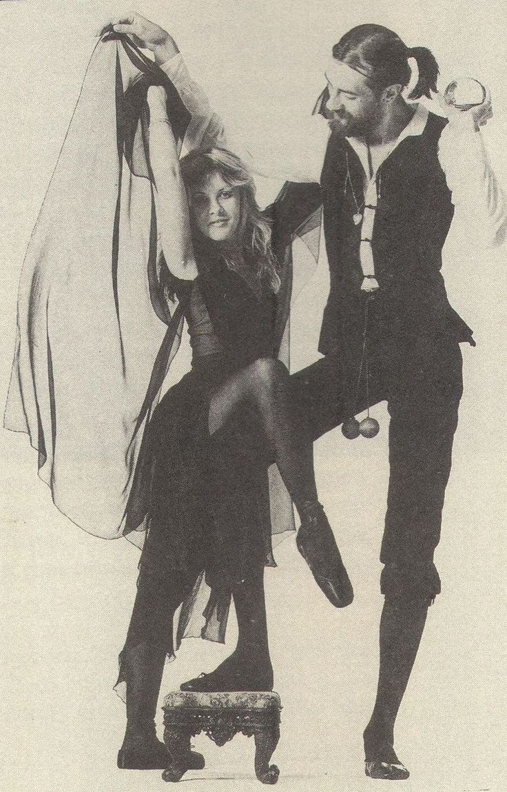 the man and woman are dressed up in black clothes, one is holding on to her dress