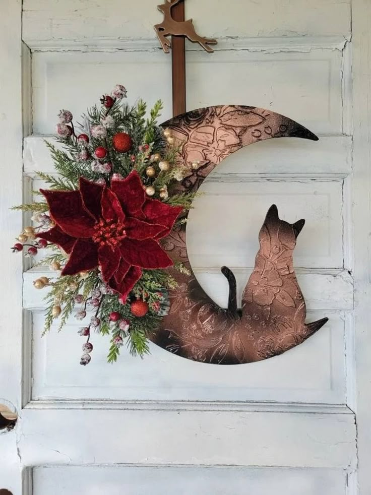 a door with a wreath and a cat sitting on the moon hanging from it's side