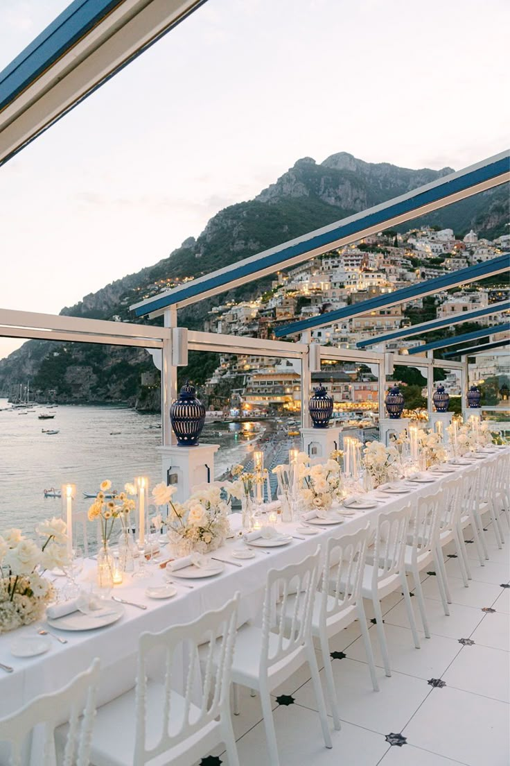 a long table is set up with white flowers and candles for an outdoor wedding reception