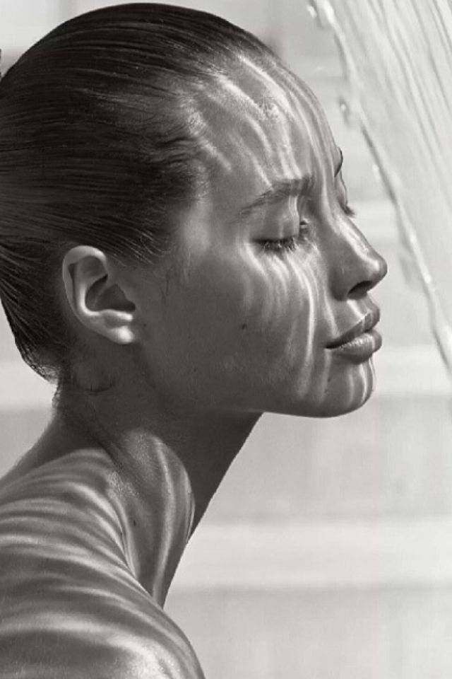 a black and white photo of a woman's face with her hair pulled back