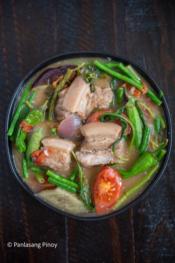 a bowl filled with meat and vegetables on top of a wooden table