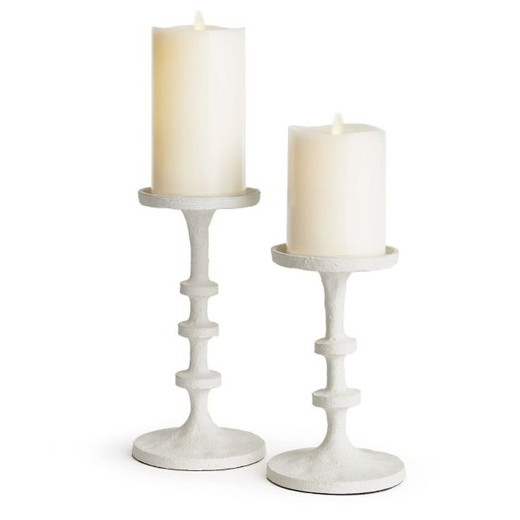 two white candles sitting next to each other