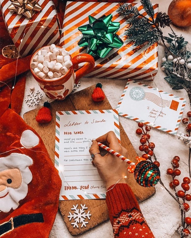 a person writing on a paper next to christmas decorations and candy canes, wrapped in santa's stockings