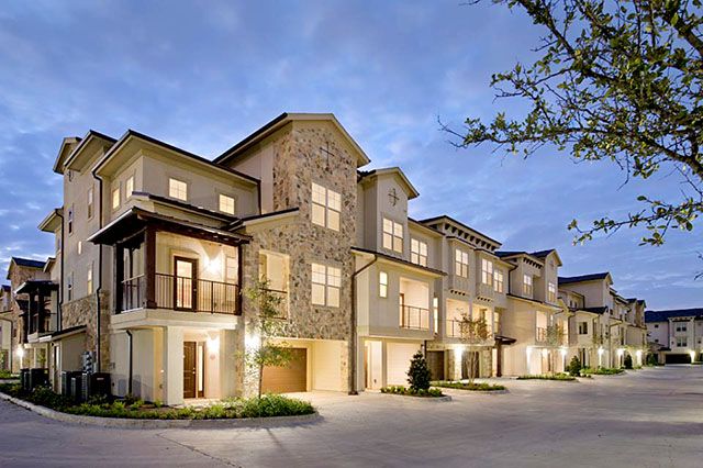 a row of townhouses at dusk with lights on