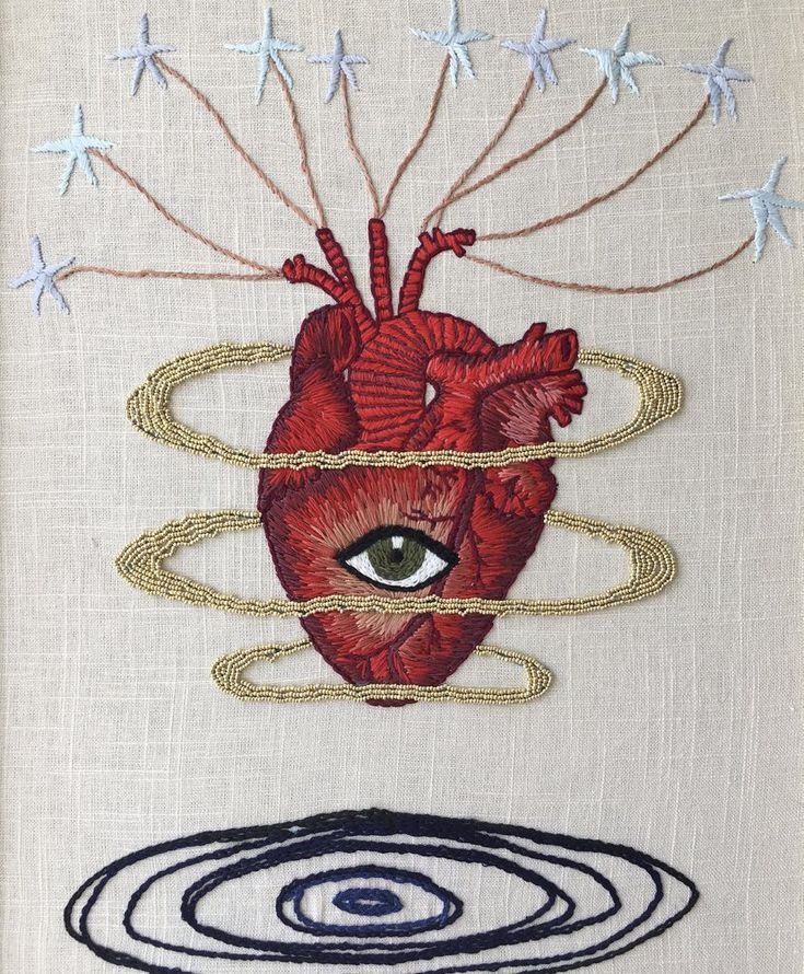 an embroidered heart and eye on a white cloth with blue circles around it, surrounded by stars