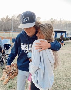 two young people hugging each other on a baseball field