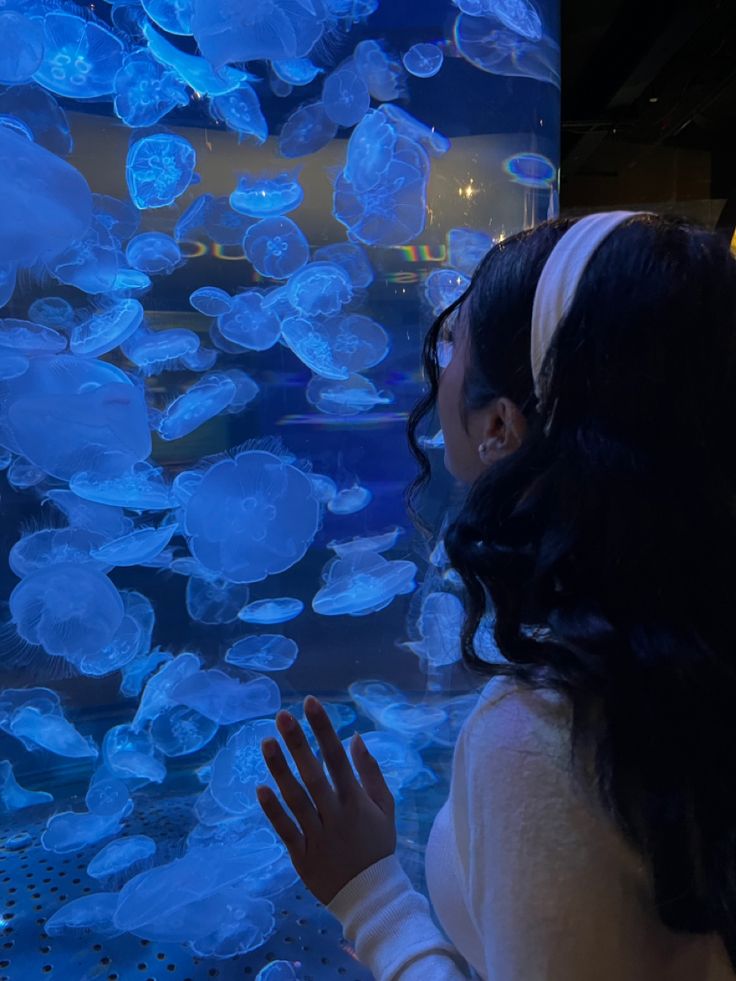 a woman looking at jellyfish in an aquarium