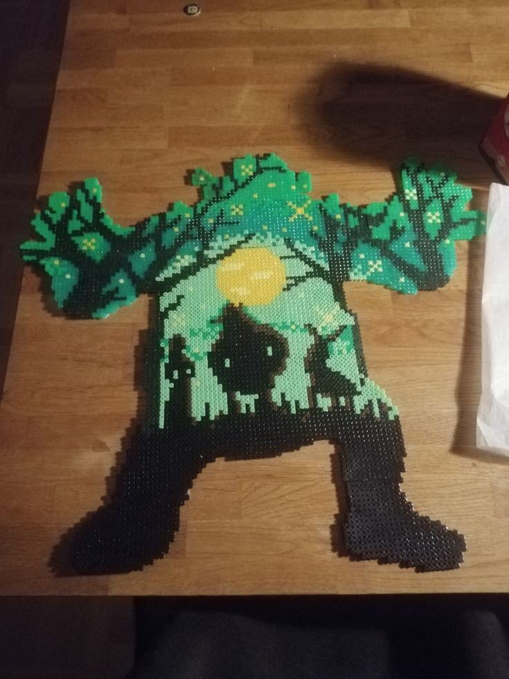 a piece of art made out of legos on a wooden table next to a paper bag