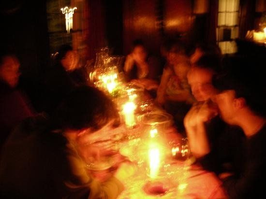 a group of people sitting around a dinner table with candles on it at night time