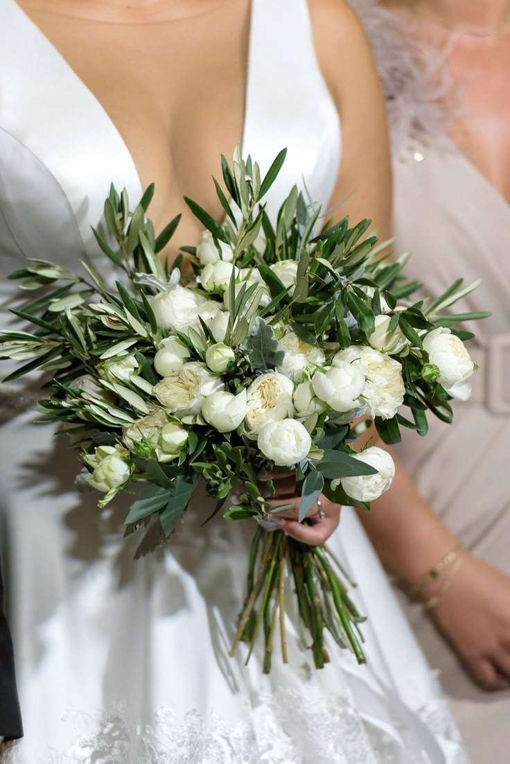 a bride holding a bouquet of white flowers