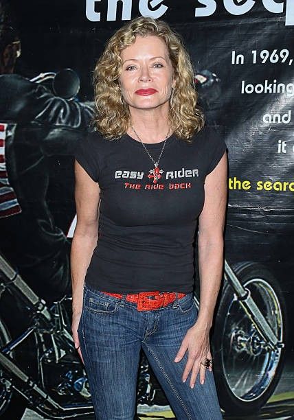 a woman standing in front of a motorcycle poster with her hands on her hips and looking at the camera