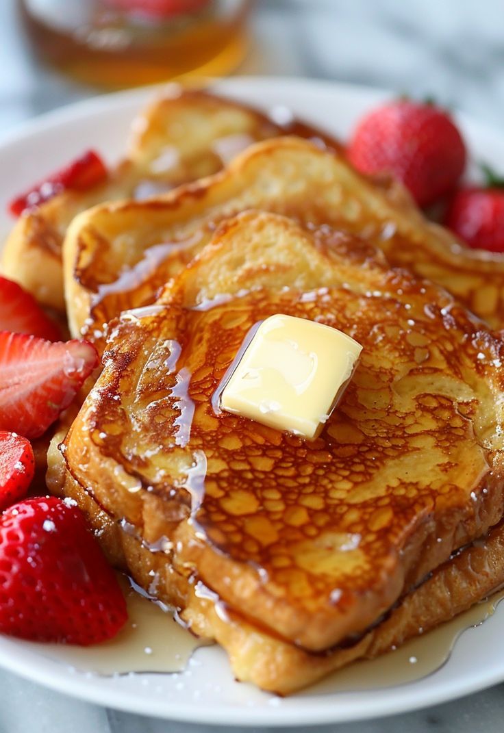 pancakes with butter and strawberries on a white plate