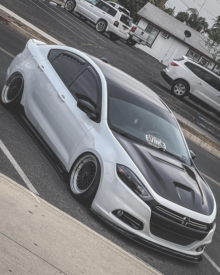 a silver car parked in a parking lot next to other cars on the side of the road