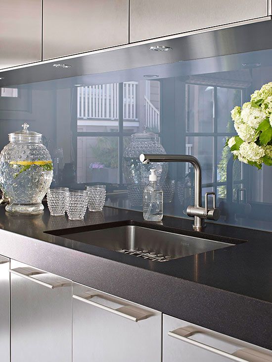 a kitchen with black counter tops and stainless steel appliances in front of a glass back splash