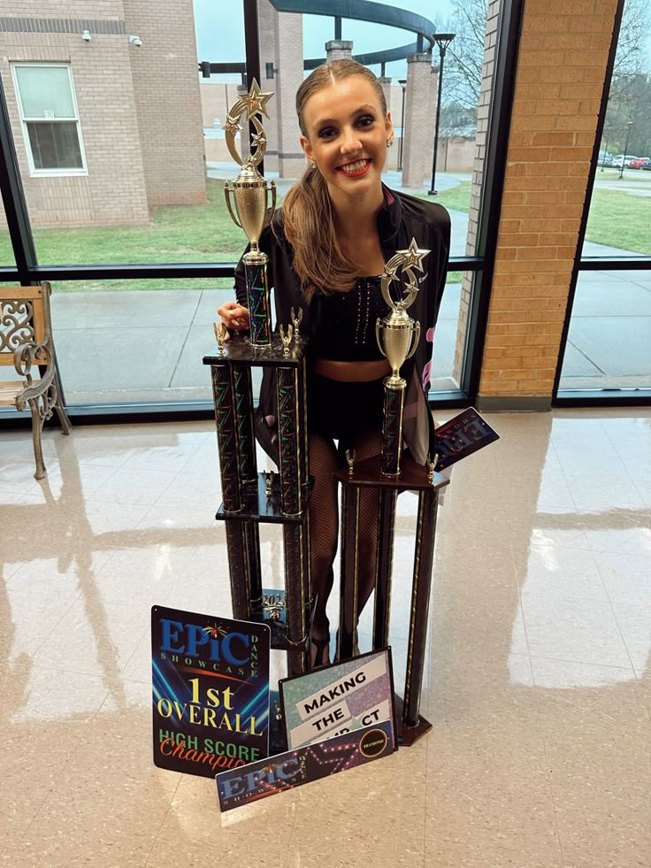 a girl is posing with trophies in front of a window