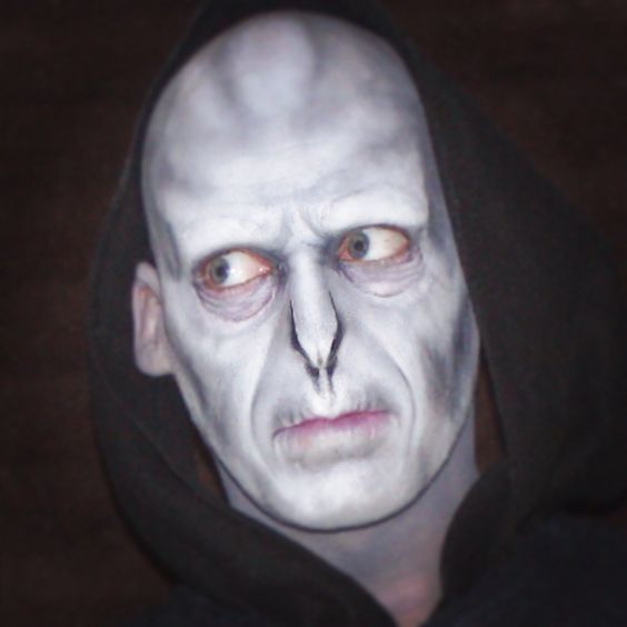 a man with white paint on his face wearing a black hoodie and looking at the camera