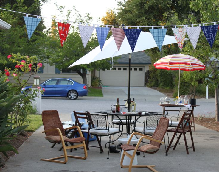 several chairs and umbrellas are set up outside on the sidewalk in front of a house