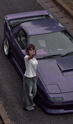 a man leaning on the hood of a purple sports car