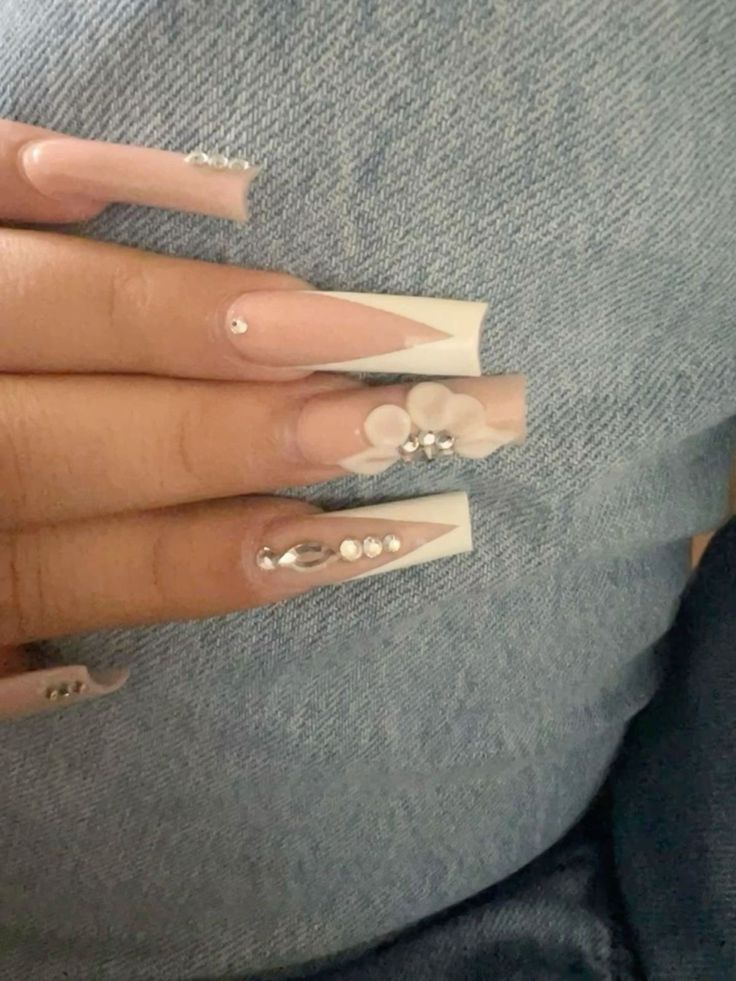 a woman's nails with white and silver designs on them, sitting on her stomach