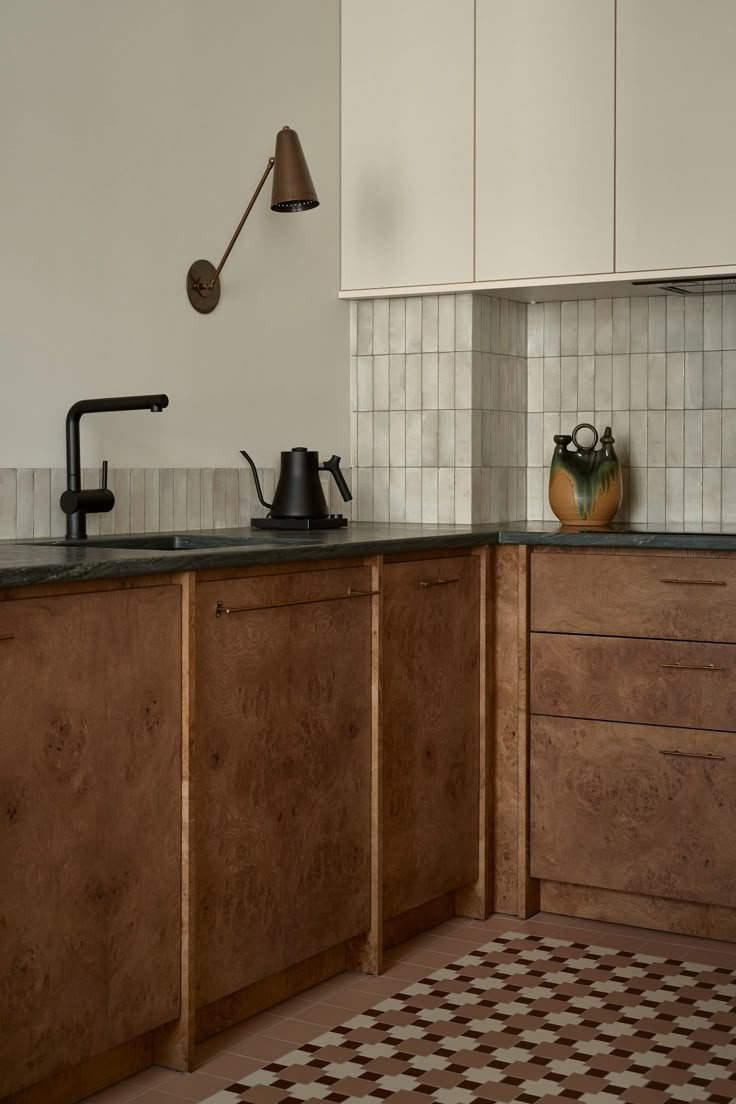 a kitchen with wooden cabinets and tile flooring, including a tea kettle on the counter