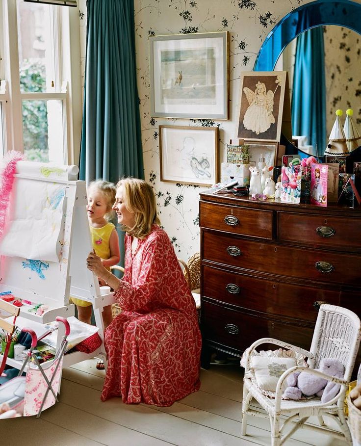 a woman and her child are sitting in front of an easel with artwork on it