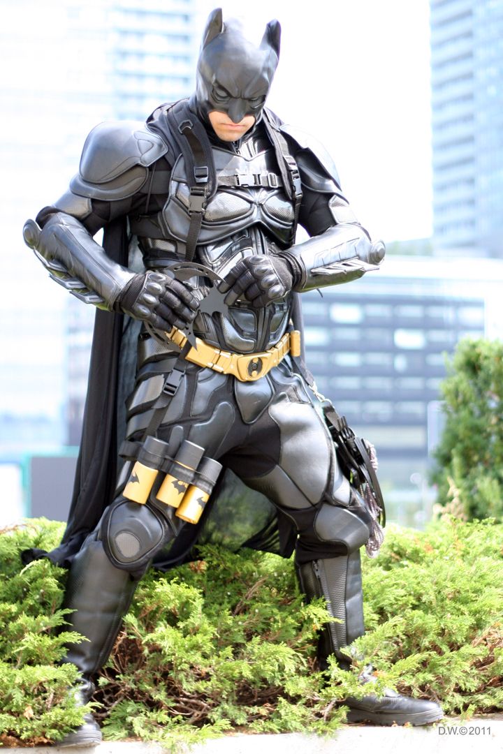 a batman statue is posed in the grass