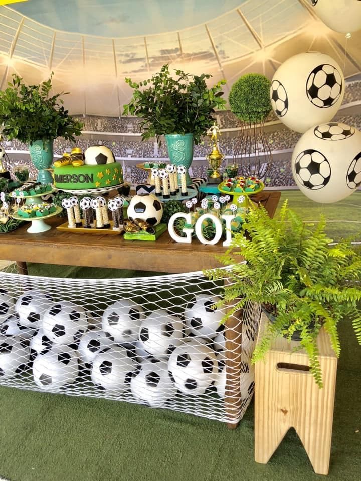 a table with soccer balls and decorations on it in a sports themed party setting at a stadium