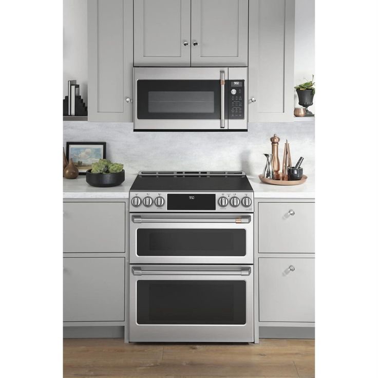 a stove top oven sitting inside of a kitchen next to white cupboards and counter tops