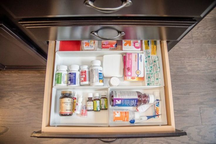 an open drawer in the middle of a stove with medicine bottles and toothpaste