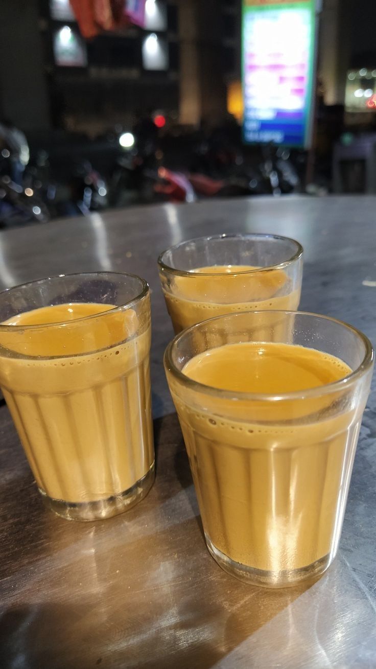 three glasses filled with liquid sitting on top of a table