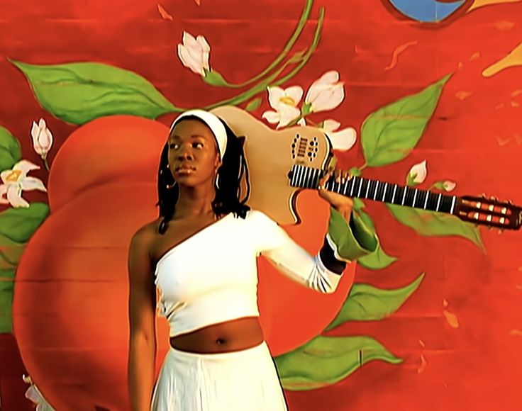 a woman holding an electric guitar in front of a painting