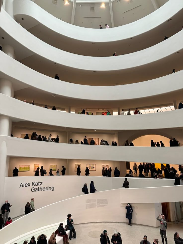 many people are standing in the middle of a large building with white walls and floors