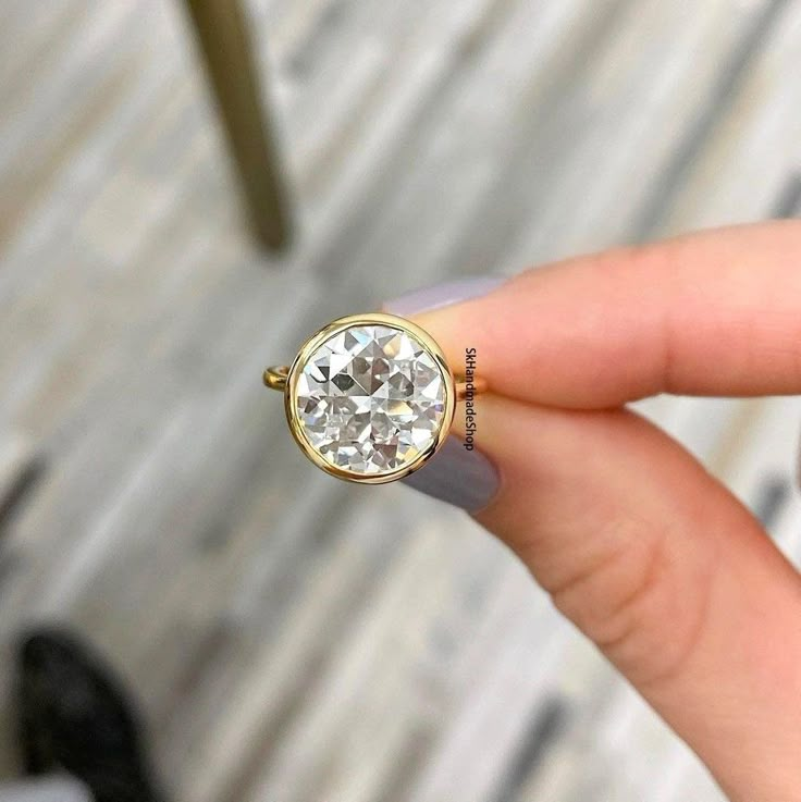 a woman's hand with a ring on it that has a diamond in the middle