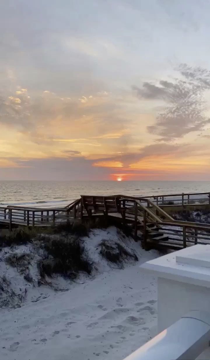 the sun is setting over the beach and boardwalks