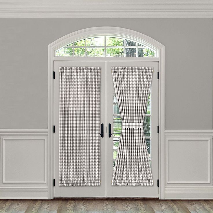 an open door with curtains on it in front of a white wall and wooden floor