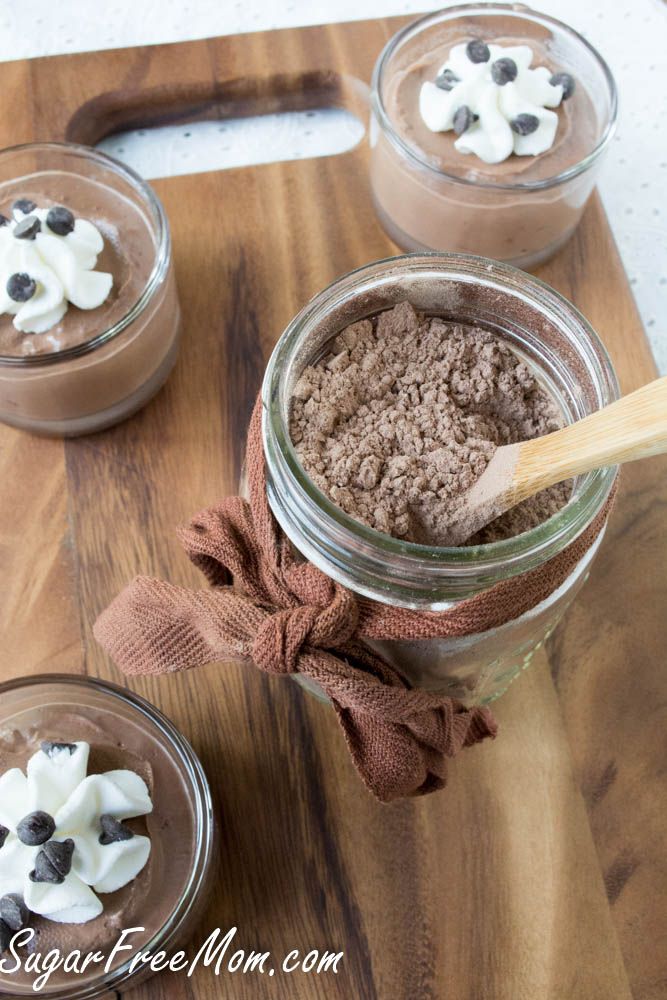 three jars filled with chocolate pudding on top of a wooden cutting board