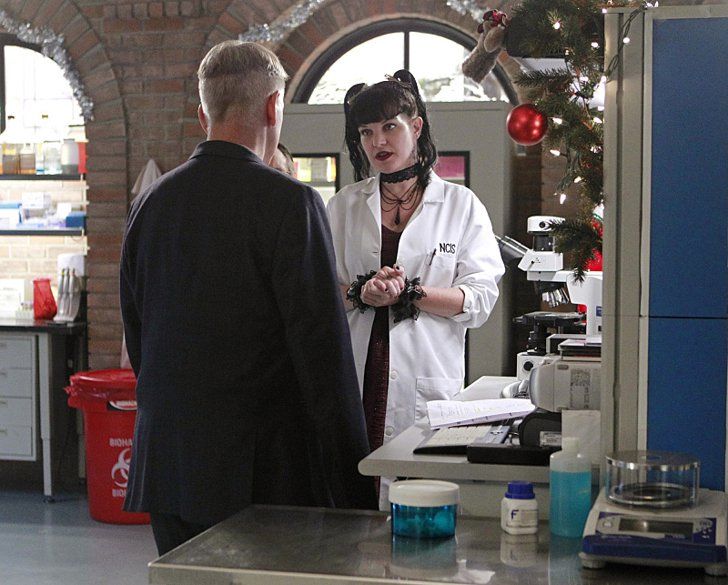 a man and woman standing in front of a counter talking to each other while wearing lab coats