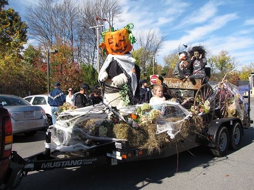 people in costumes are riding on the back of a trailer decorated with hay and pumpkins