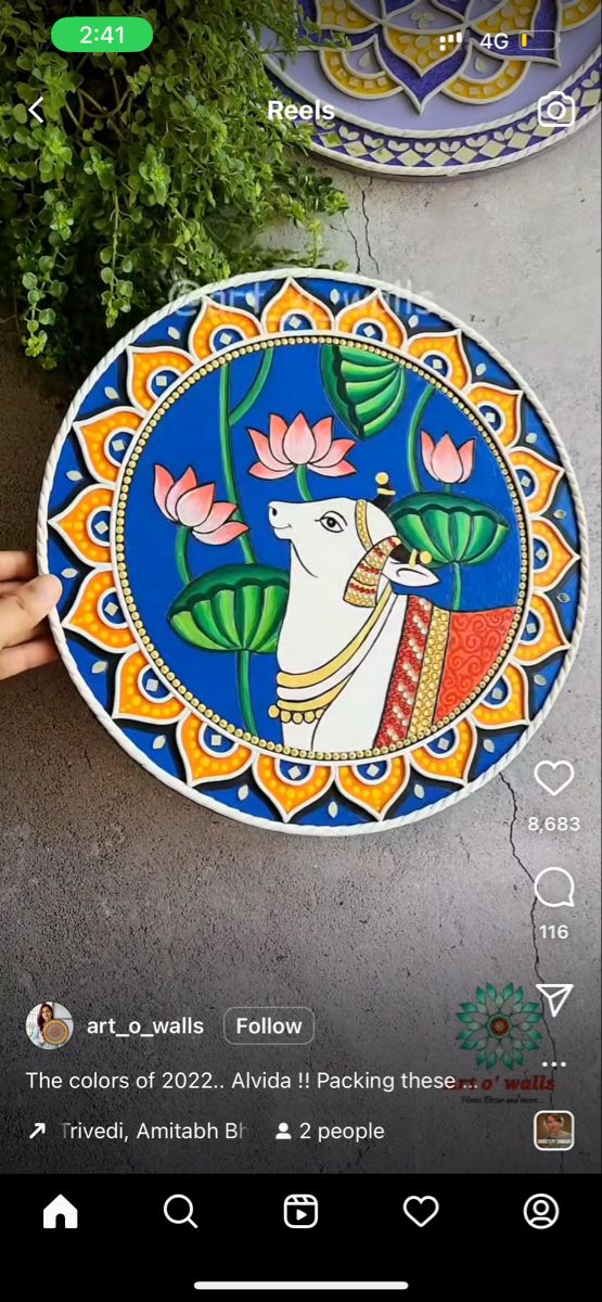 someone is holding up a colorful plate with an animal on it and flowers in the background