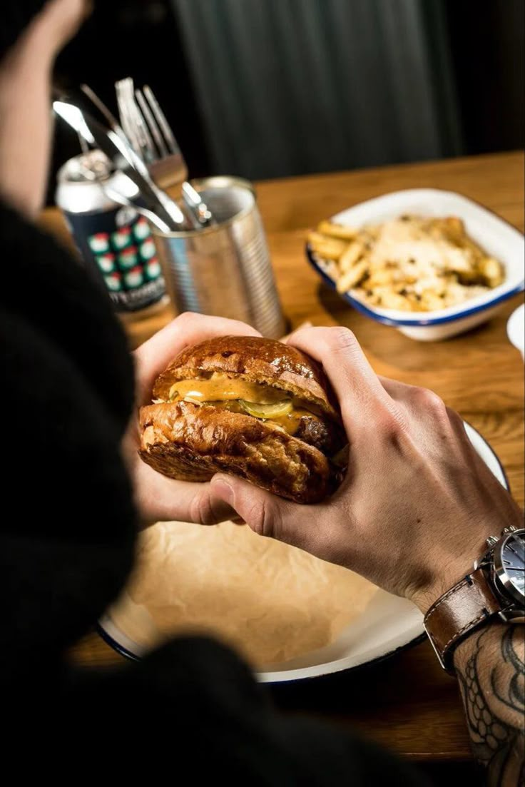 a person sitting at a table eating a sandwich