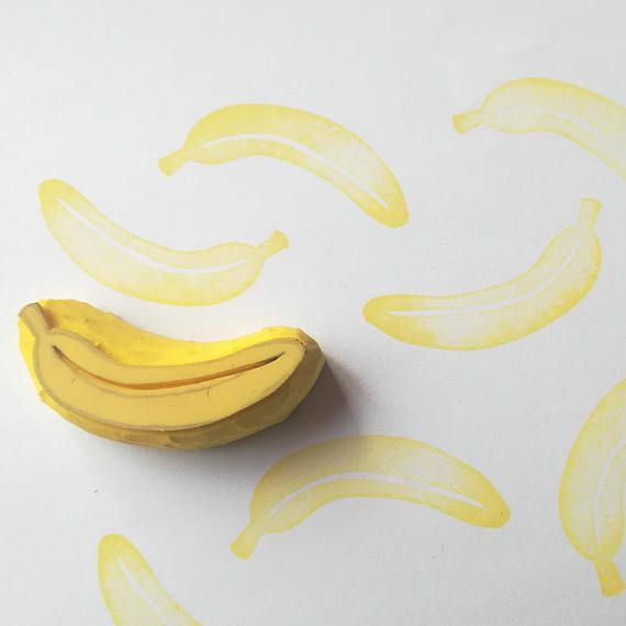 a banana sitting on top of a white table next to yellow wallpaper with bananas drawn on it