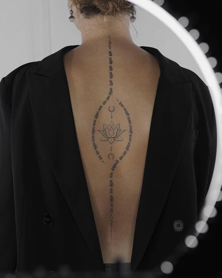 the back of a woman's neck with a lotus tattoo