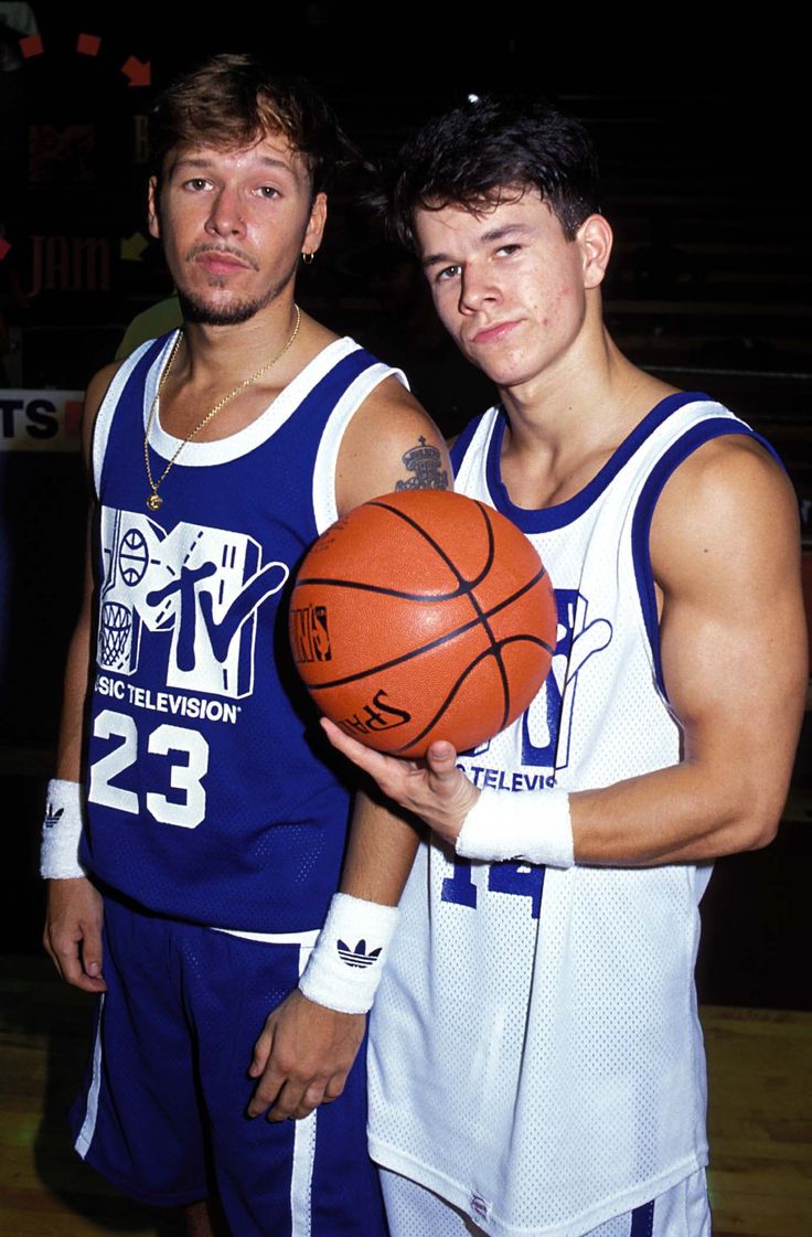 two young men holding a basketball in their hands and posing for the camera with each other