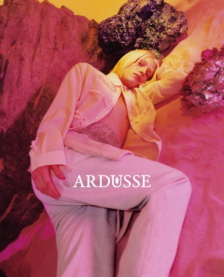 a woman sitting on top of a bed wearing white pants and a yellow shirt with the words ardusse