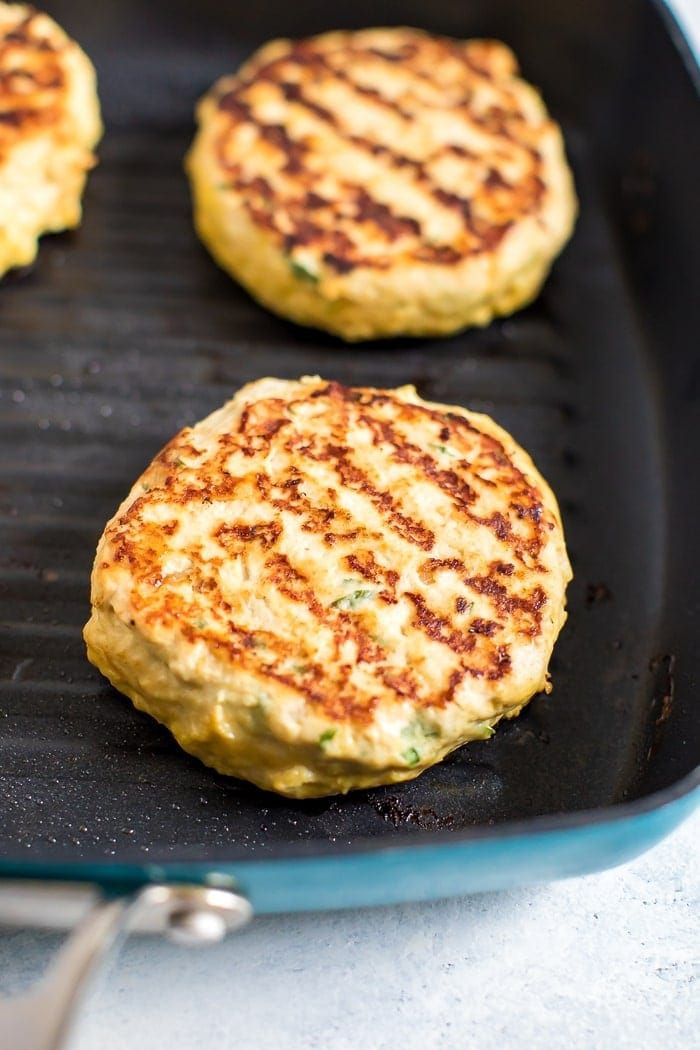 three burger patties cooking on a grill pan