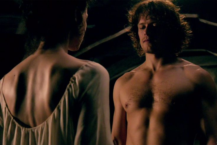 two people standing in the dark with one person looking at another man's shirtless torso